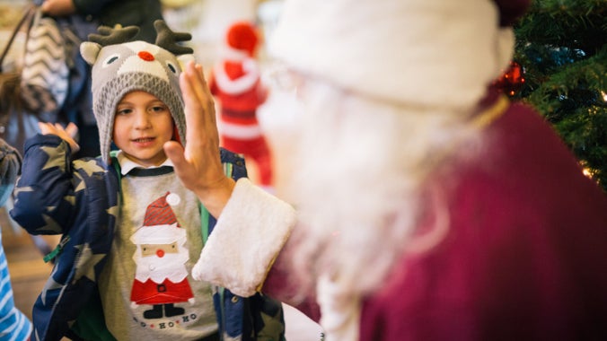 A young boy high-fiving Father Christmas in his grotto at Erddig, Wales
